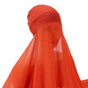 Un conjunto de hijab y chal de gasa naranja brillante drapeado sobre una cabeza.