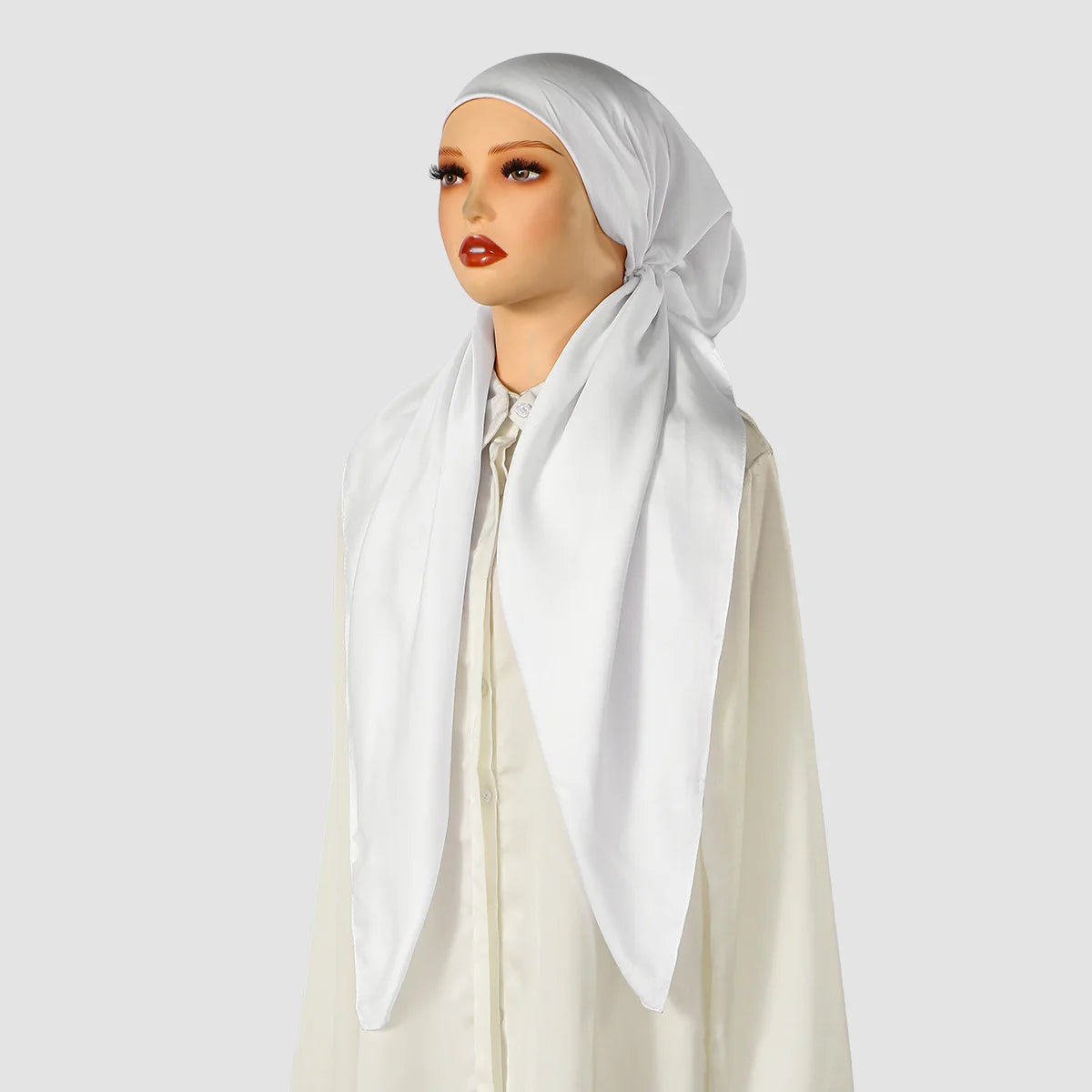Eine Frau trägt einen weißen Satin-Seiden-Instant-Hijab und ein cremefarbenes Oberteil.