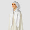 A woman wearing an elegant white satin silk instant hijab scarf and a cream-colored garment.