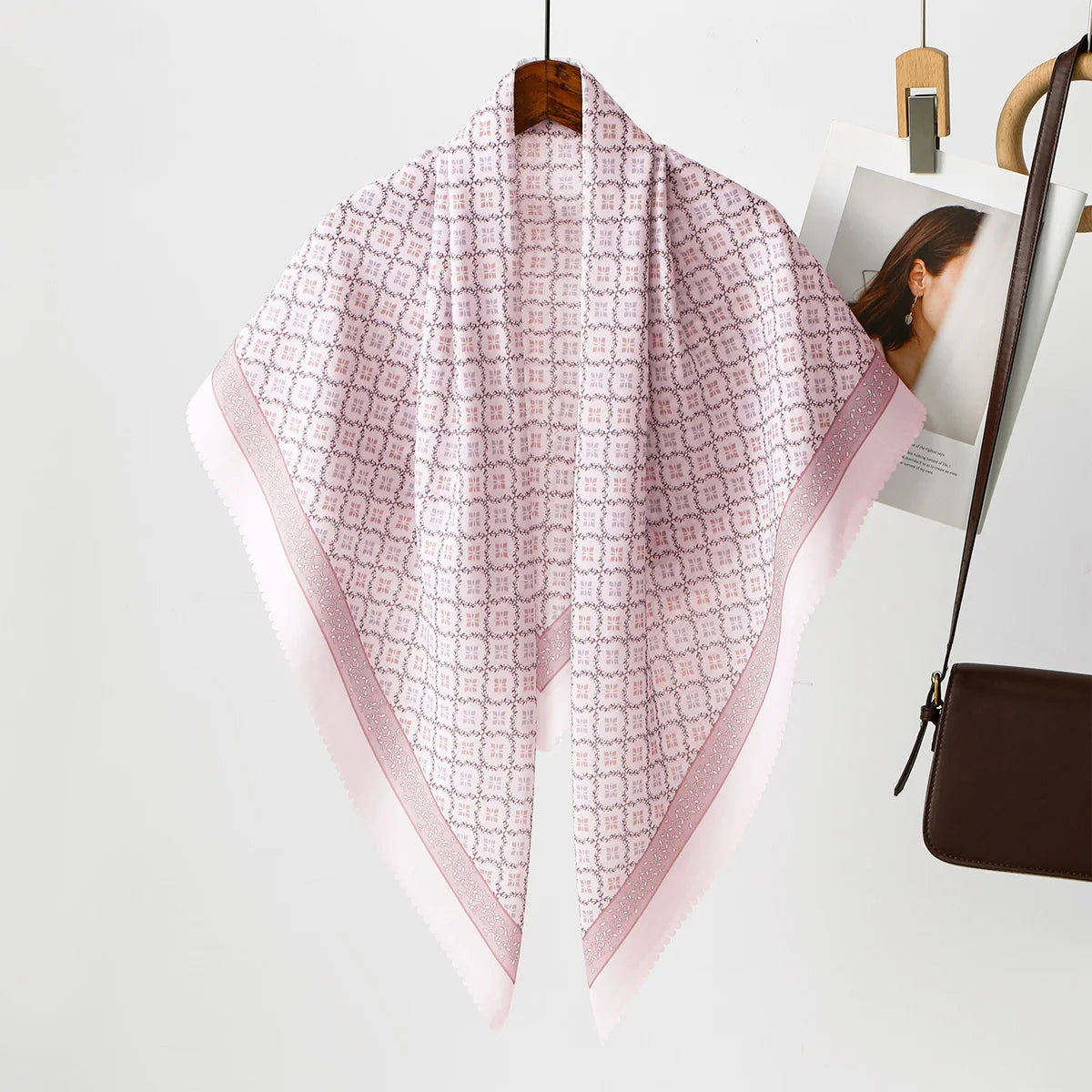 Rosa blumiges quadratisches Hijab-Tuch auf einem Holzbügel vor weißem Hintergrund.