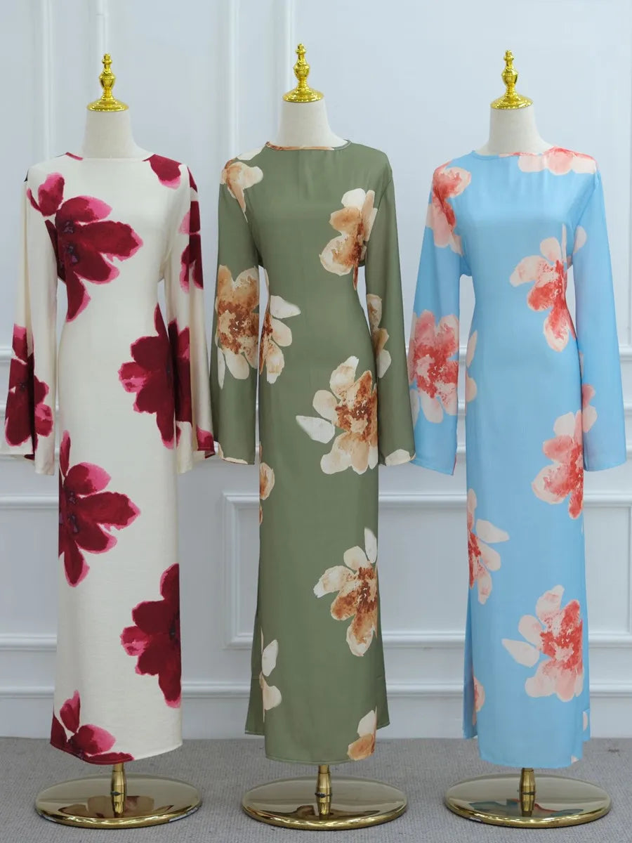 A full-length display of three luxury floral print abaya kaftan dresses in shades of green, pink, and blue.