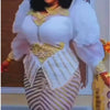 A woman wearing a white and gold sequin African party dress with puffy sleeves and a layered bodice.