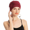 Eine Frau trägt eine tiefrote, floral bestickte Hijab-Turbanmütze und ein schwarzes Tanktop.