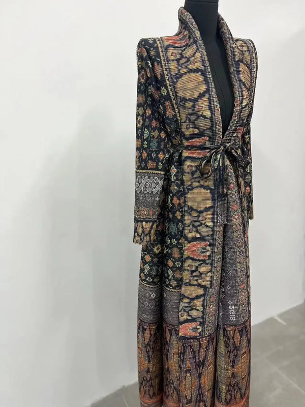 A dark patterned pleated long sleeve trench coat displayed on a black mannequin.