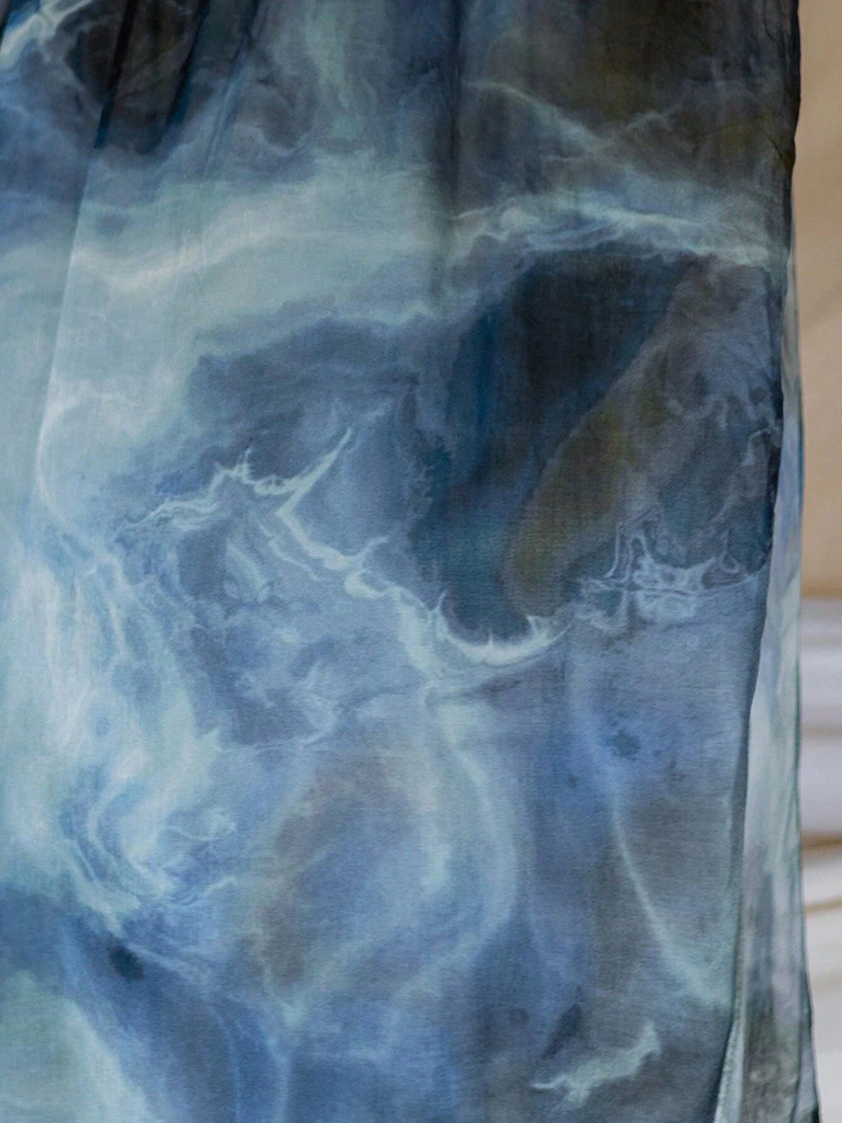 Nahaufnahme eines fließenden, aquarellgedruckten Stoffschals in Blau- und Grautönen.