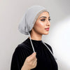 Eine Frau trägt eine silberne Hijab-Kappe mit Gold-Strass und einem schwarzen Samt-Oberteil.