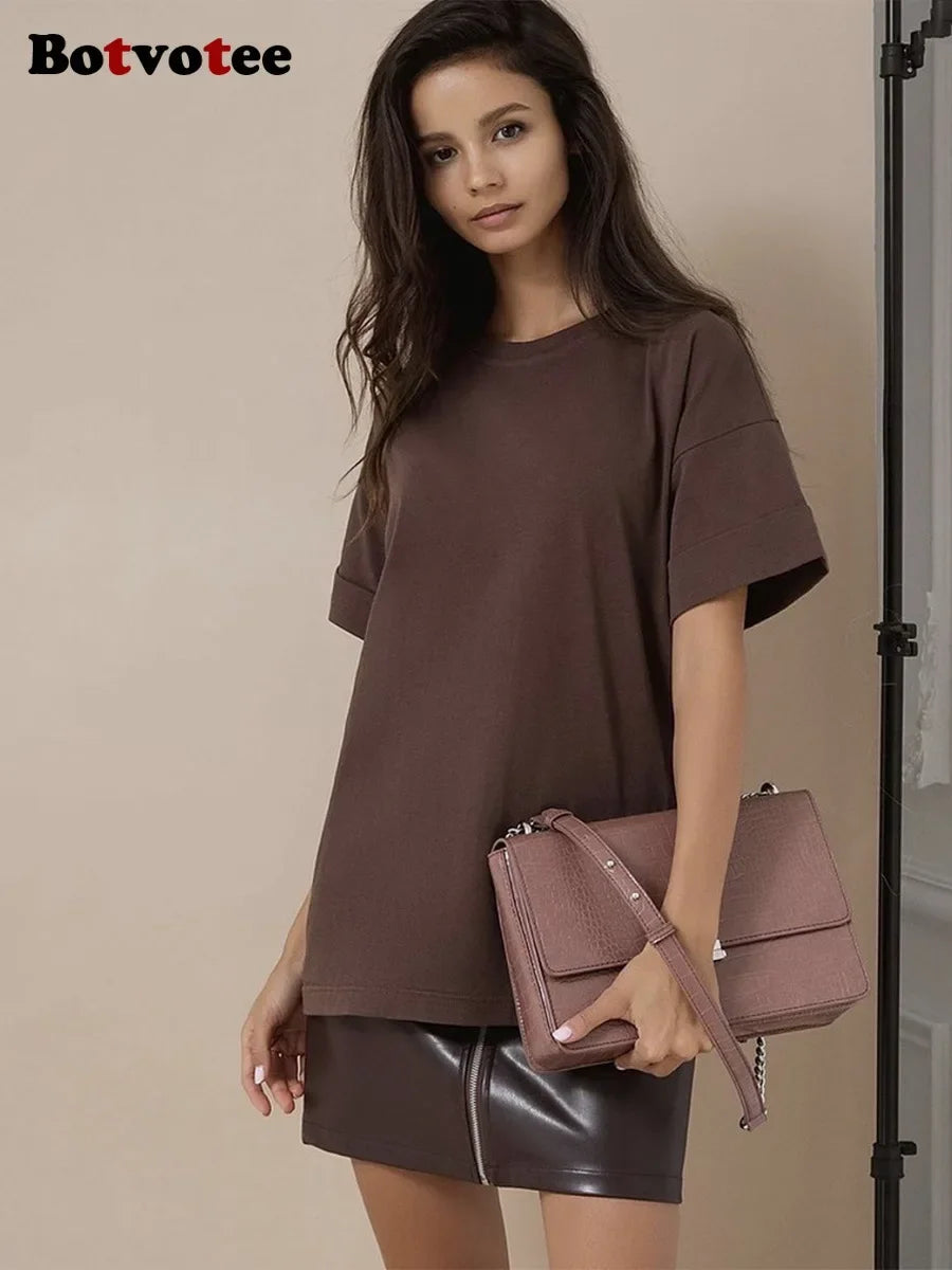Una modelo vistiendo una camiseta básica de algodón marrón oversize y una falda de cuero.