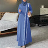 Eine Frau trägt ein elegantes blaues Spitzen-Abaya-Kleid mit langen Ärmeln und einen passenden Hijab drinnen.