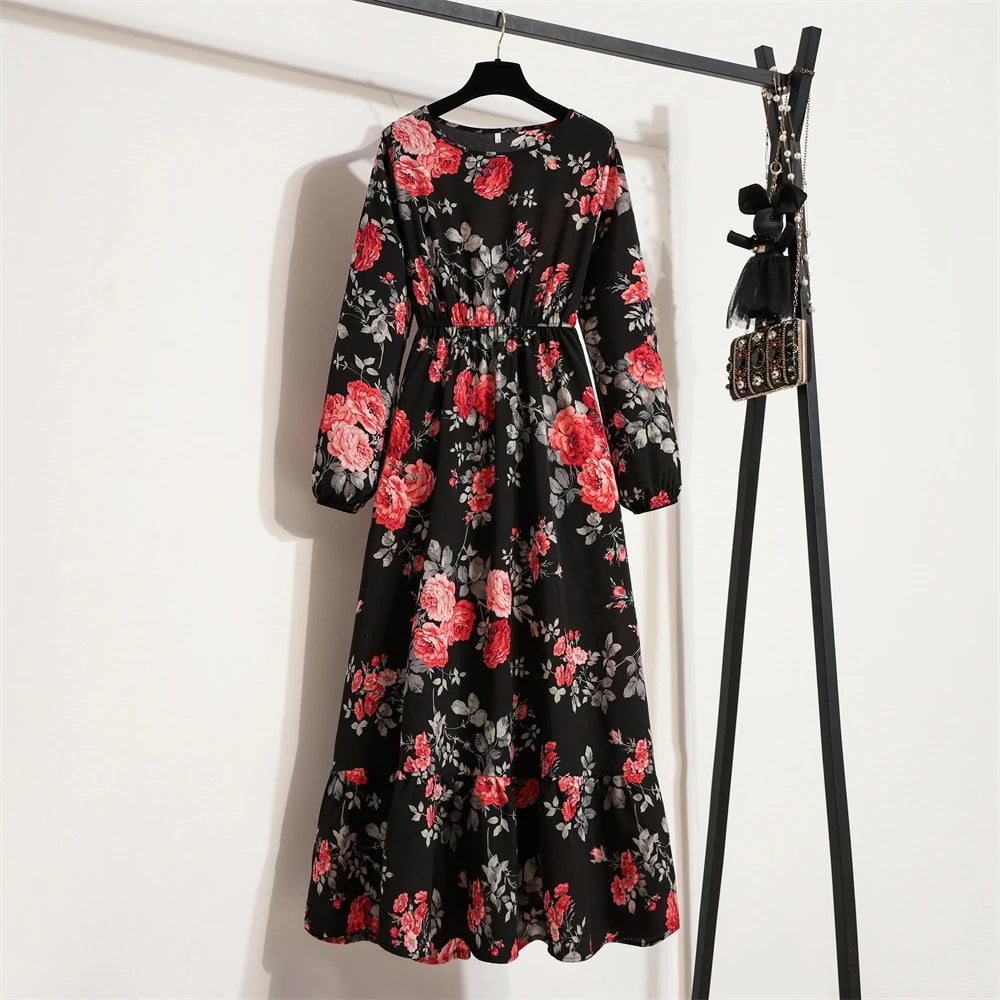 Schwarzes Maxi-Kleid mit floralem Muster in Rosa und Rot, hängt an einem schwarzen Kleiderständer.
