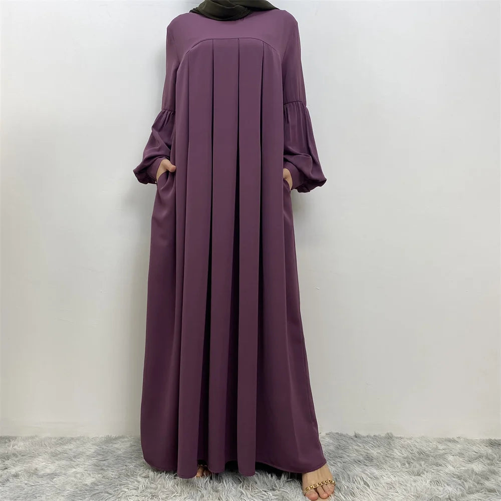 Eine Frau trägt ein elegantes langes lila islamisches Kleid und einen passenden Hijab.