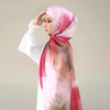 Eine Frau trägt einen eleganten bedruckten Seideschal-Hijab in rosa und beige Aquarelltönen.