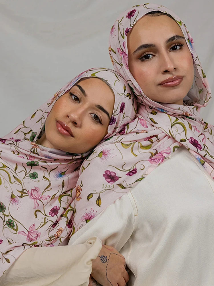 Une femme portant un hijab floral aquarelle rose et un haut crème.