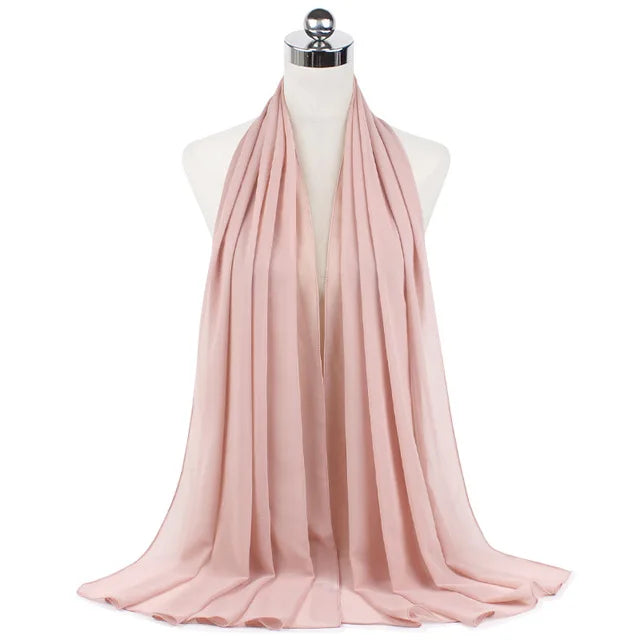 A soft, dusty rose chiffon hijab scarf draped around a mannequin's neck.