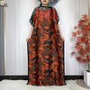 Eine Frau trägt ein orange-schwarz abstraktes Kaftankleid mit weitem Schnitt.