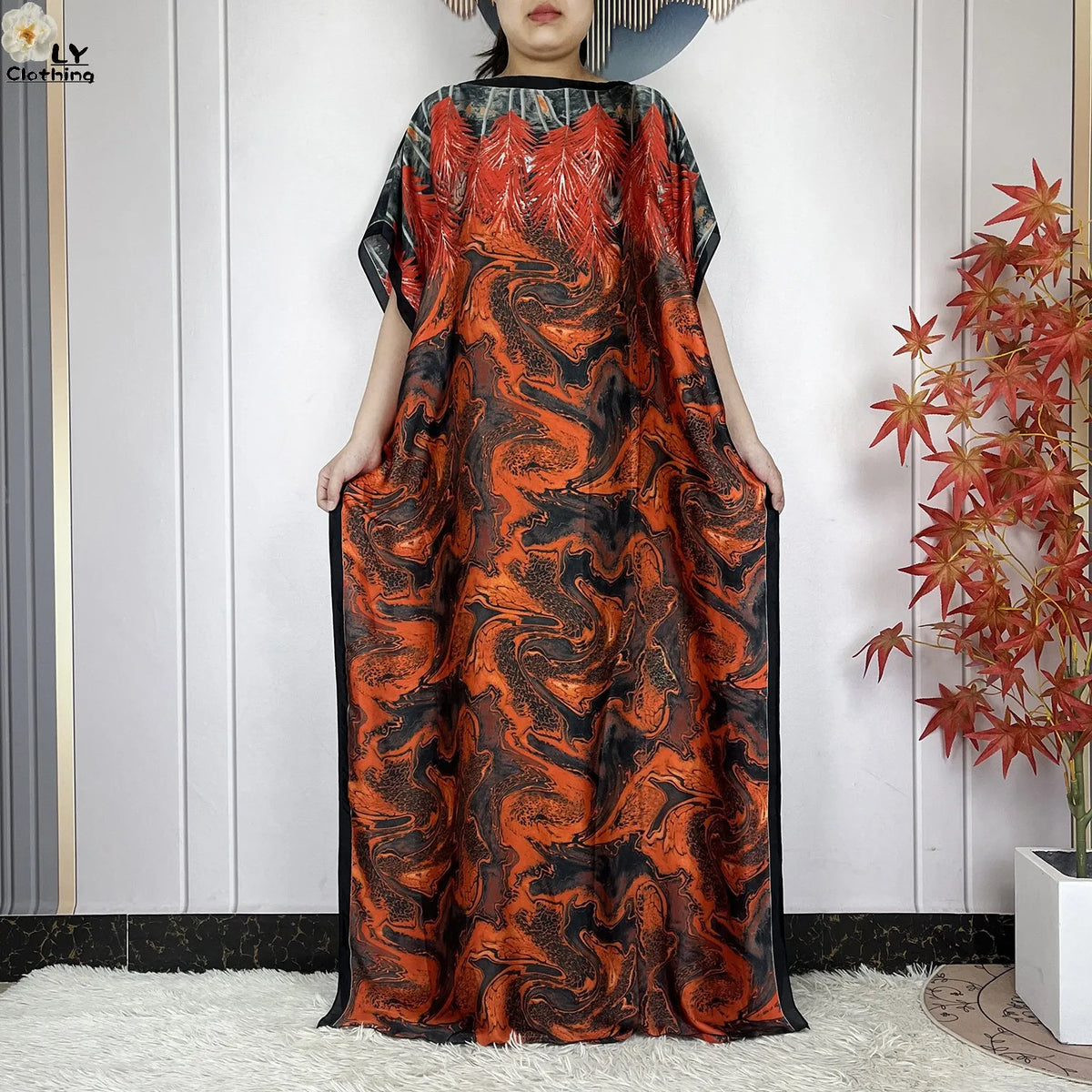Eine Frau trägt ein orange-schwarz abstraktes Kaftankleid mit weitem Schnitt.