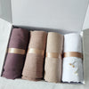 Set von vier zerknitterten Baumwoll-Hijab-Schals in Mauve-, Beige- und Weißtönen, verpackt in einer Kartonbox.