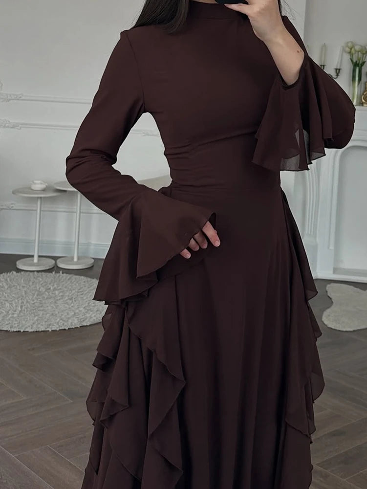 A dark brown elegant high-waisted long-sleeve A-line maxi dress shown on a model.
