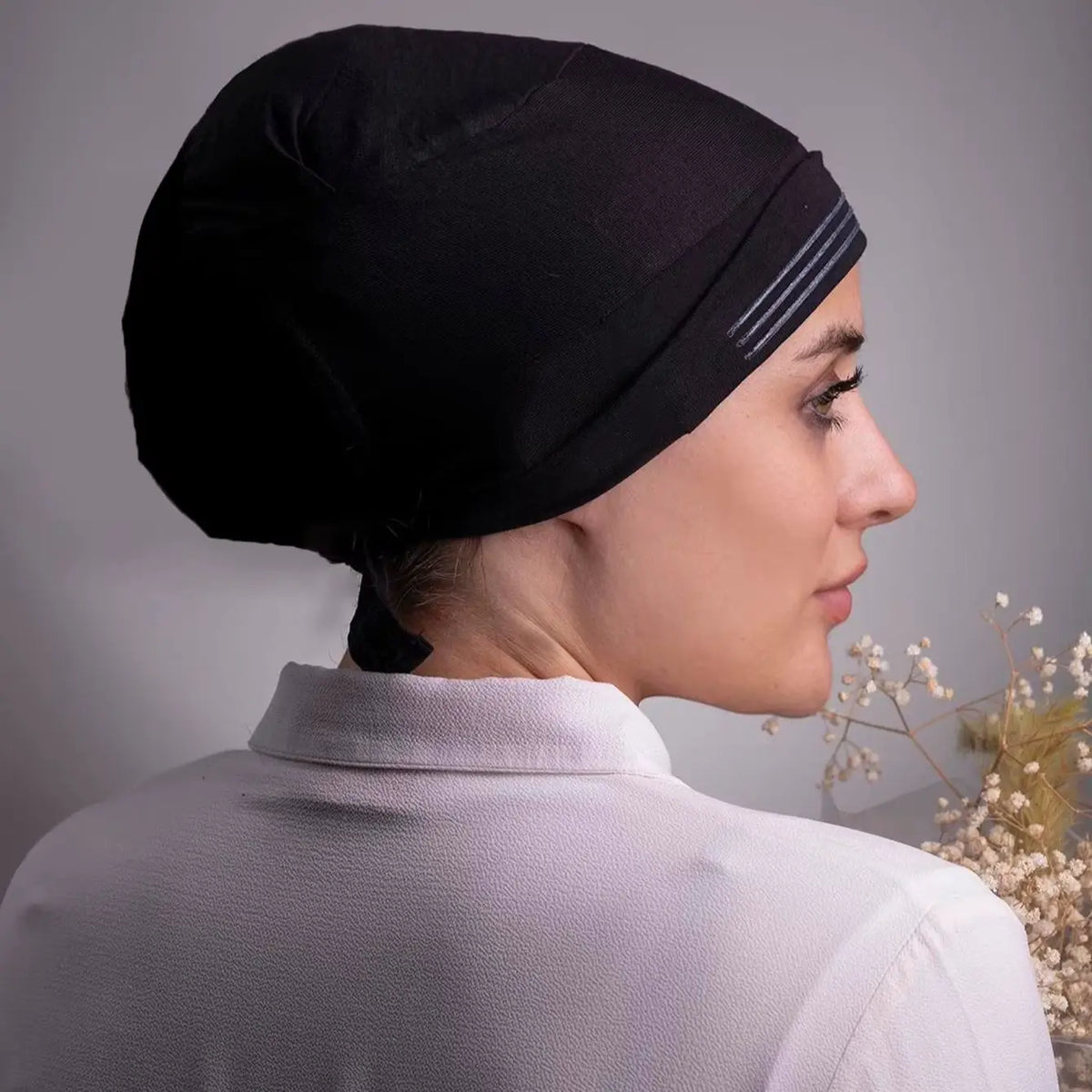 Gros plan d'une femme portant un foulard turban noir en stretch instant et une chemise blanche.