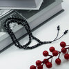 Black beaded tasbih for Islamic prayer and meditation resting on a book.