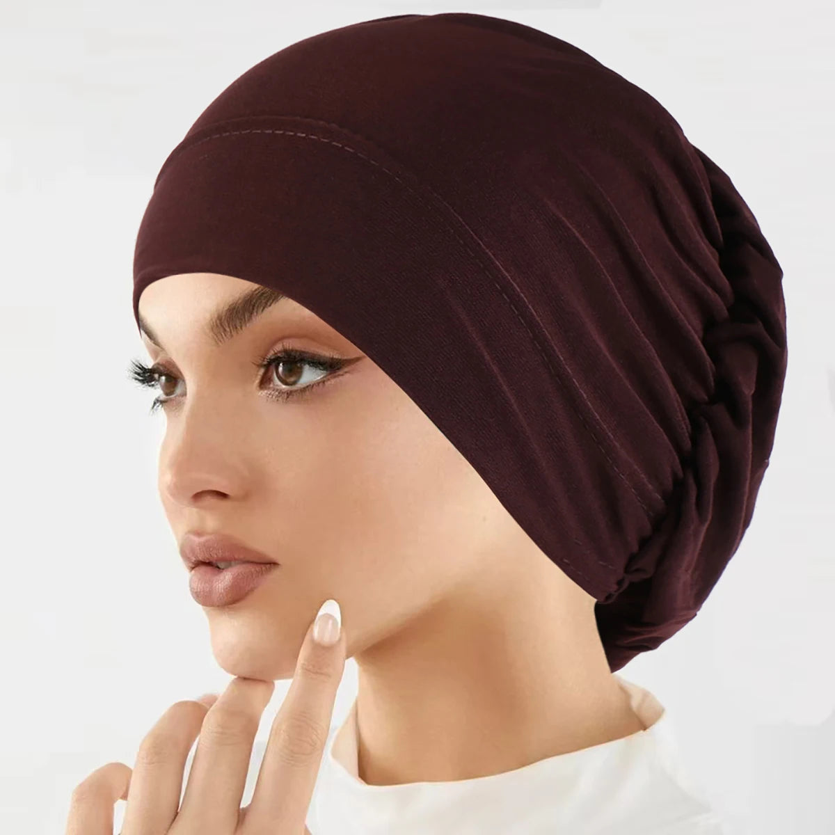 Nahaufnahme einer Frau mit einem dunkelburgunderfarbenen Stretch-Turbanmütchen.