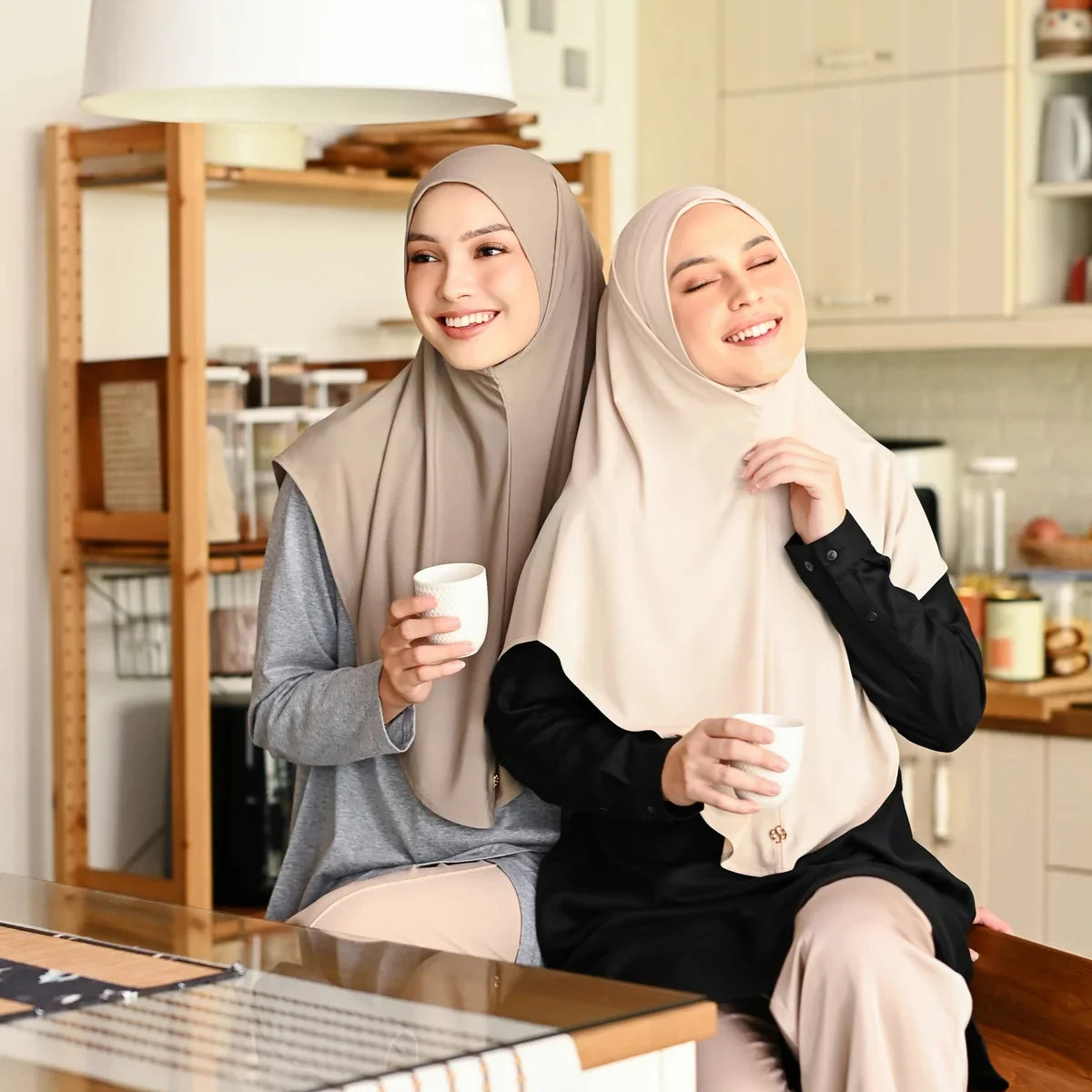 Une femme portant un foulard instant en coton chanvre beige, avec un turban, sourit tout en tenant une tasse.