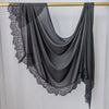 Hijab de malla negra con estampado doble y drapeado sobre un perchero dorado.