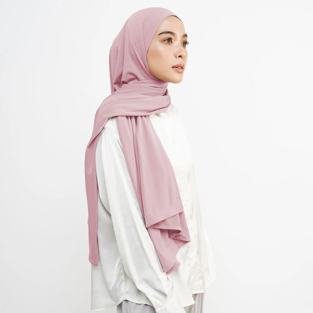 Eine Frau trägt einen weichen rosa Instant-Hijab-Schal über einem weißen Top.
