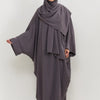Eine Frau trägt ein traditionelles, bedeckendes Abaya-Set in anthrazitgrauer Farbe mit passender Hijab.