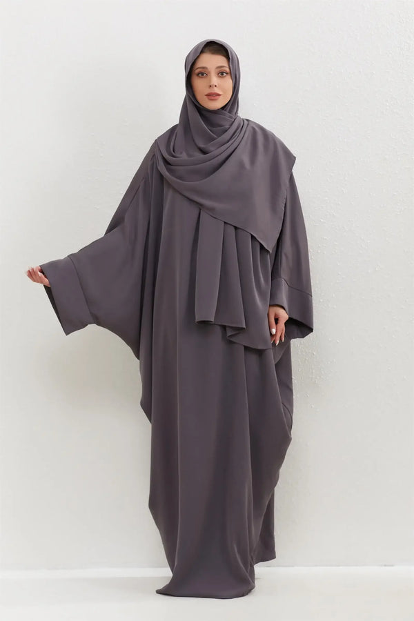 A woman wearing a charcoal gray traditional modest abaya set with a matching hijab.