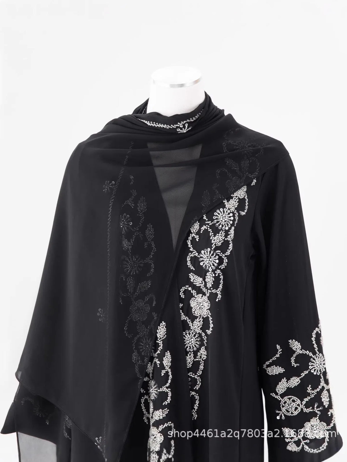 Black sheer abaya with gold floral beaded embroidery displayed on a white mannequin.