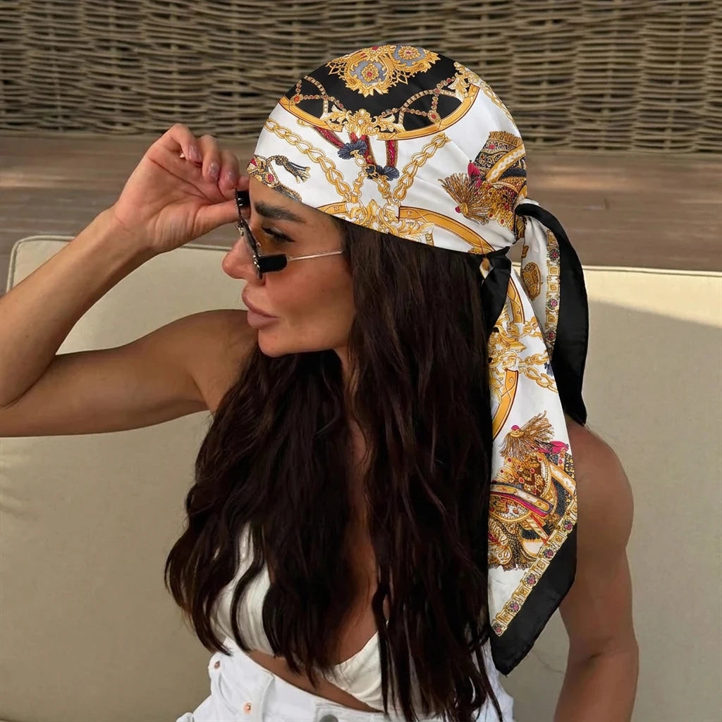 A woman wearing an elegant silk dot print scarf tied around her hair and neck.
