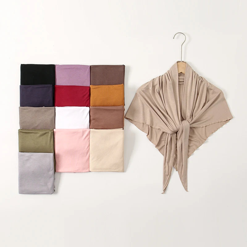 Collection de foulards hijabs en jersey triangle pliés, dans diverses tons sourds et terreux, sur fond blanc.