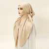Une femme portant un foulard carré beige et du tissu assorti drapé autour de son cou.