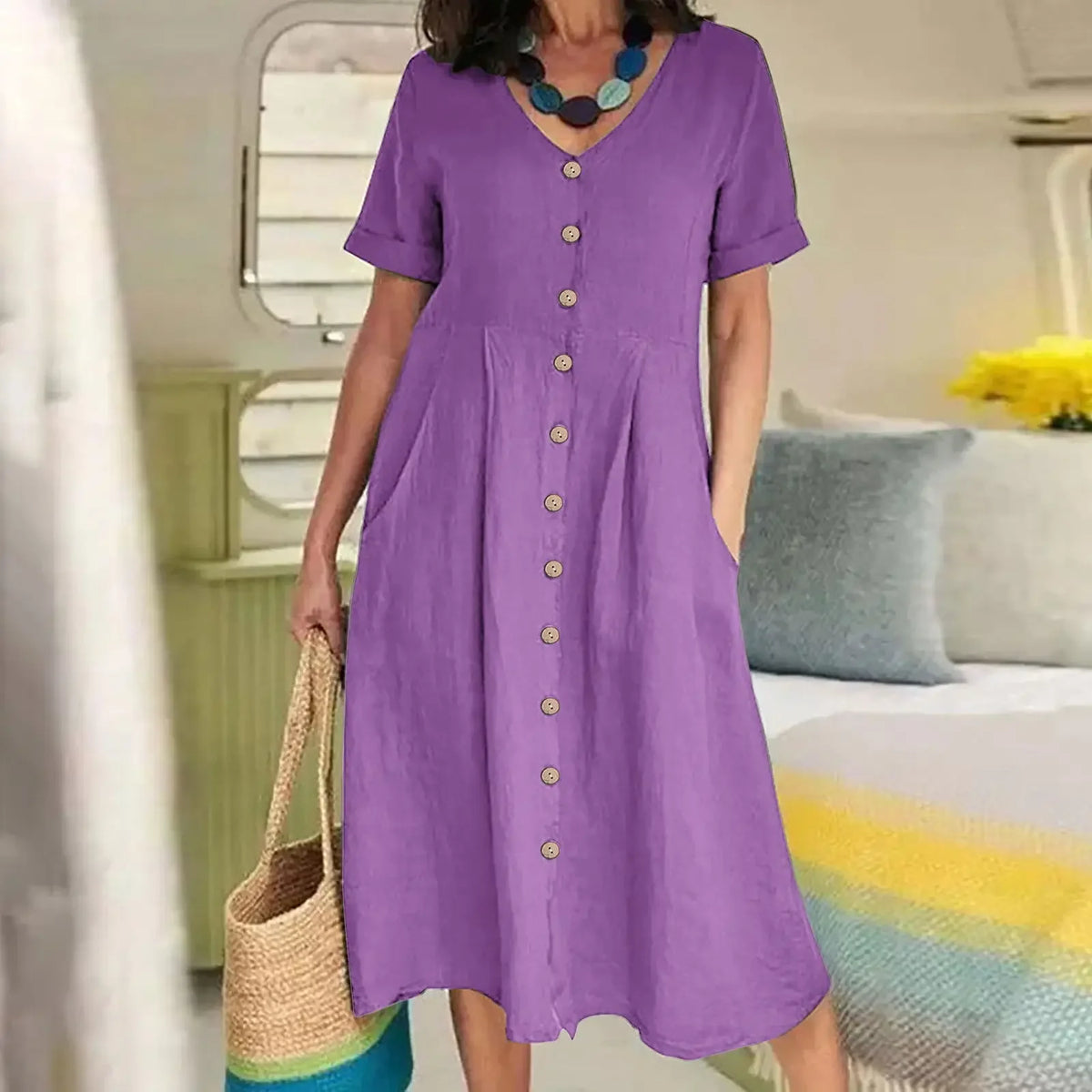 Lila Baumwoll- und Hanf-V-Ausschnittkleid bei einer Person in heller Innenraumumgebung.