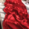 Leuchtend rote crinkelige Satin-Chiffon-Hijab drapiert und gefaltet auf weißem Untergrund.