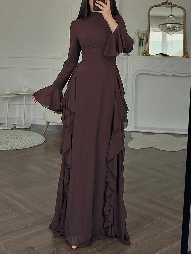 A full-length, dark brown elegant maxi dress with a high neckline and long sleeves displayed indoors.