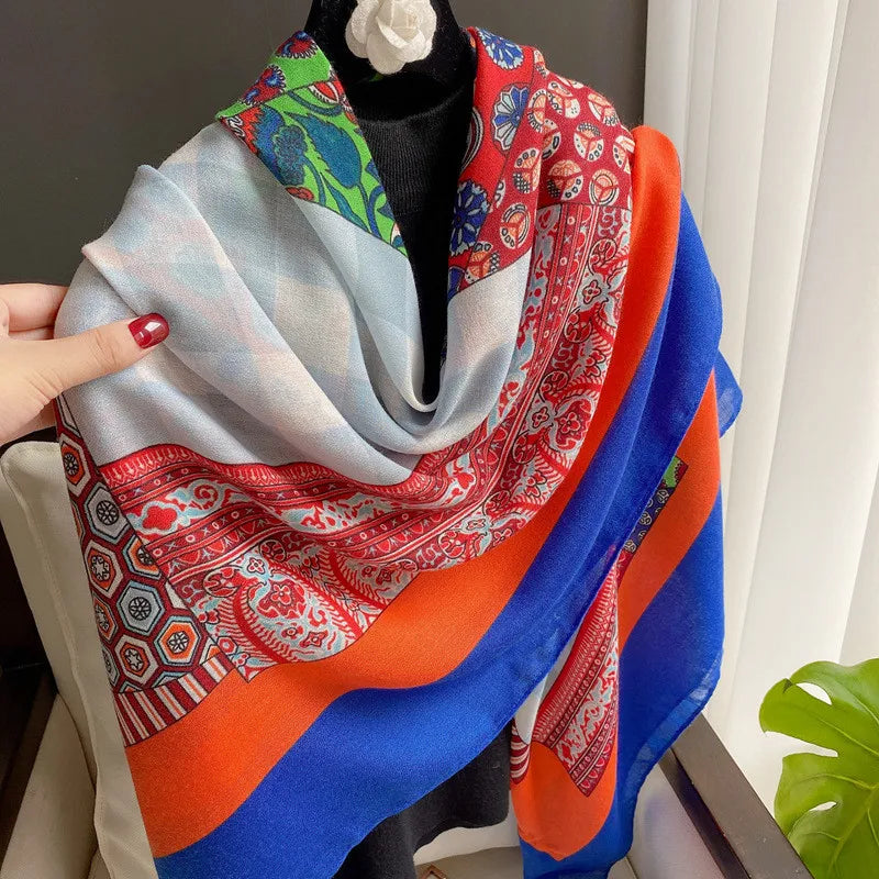 Leuchtender Viskose-Schal mit blauen, orangen und roten Blumenmustern über einem schwarzen Kleidungsstück.