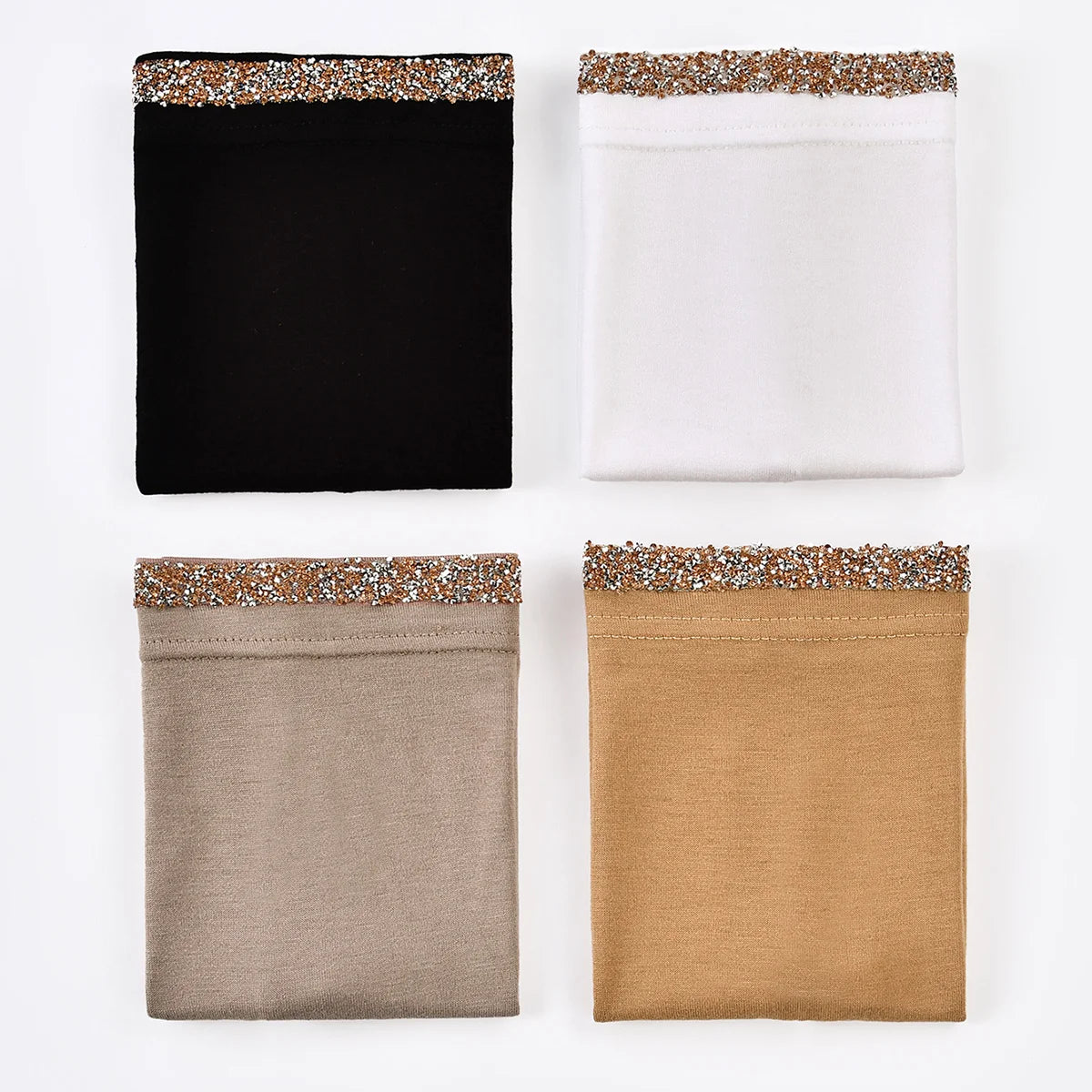 Tres pañuelos interiores doblados en negro, blanco y beige con ribetes brillantes.