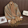 Una pashmina de lujo con patrón beige y marrón drapeada sobre una superficie de cuero marrón oscuro.