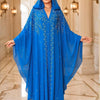 Una mujer modela un abaya maxi de color azul real fluida con mangas de murciélago en un entorno interior lujoso.