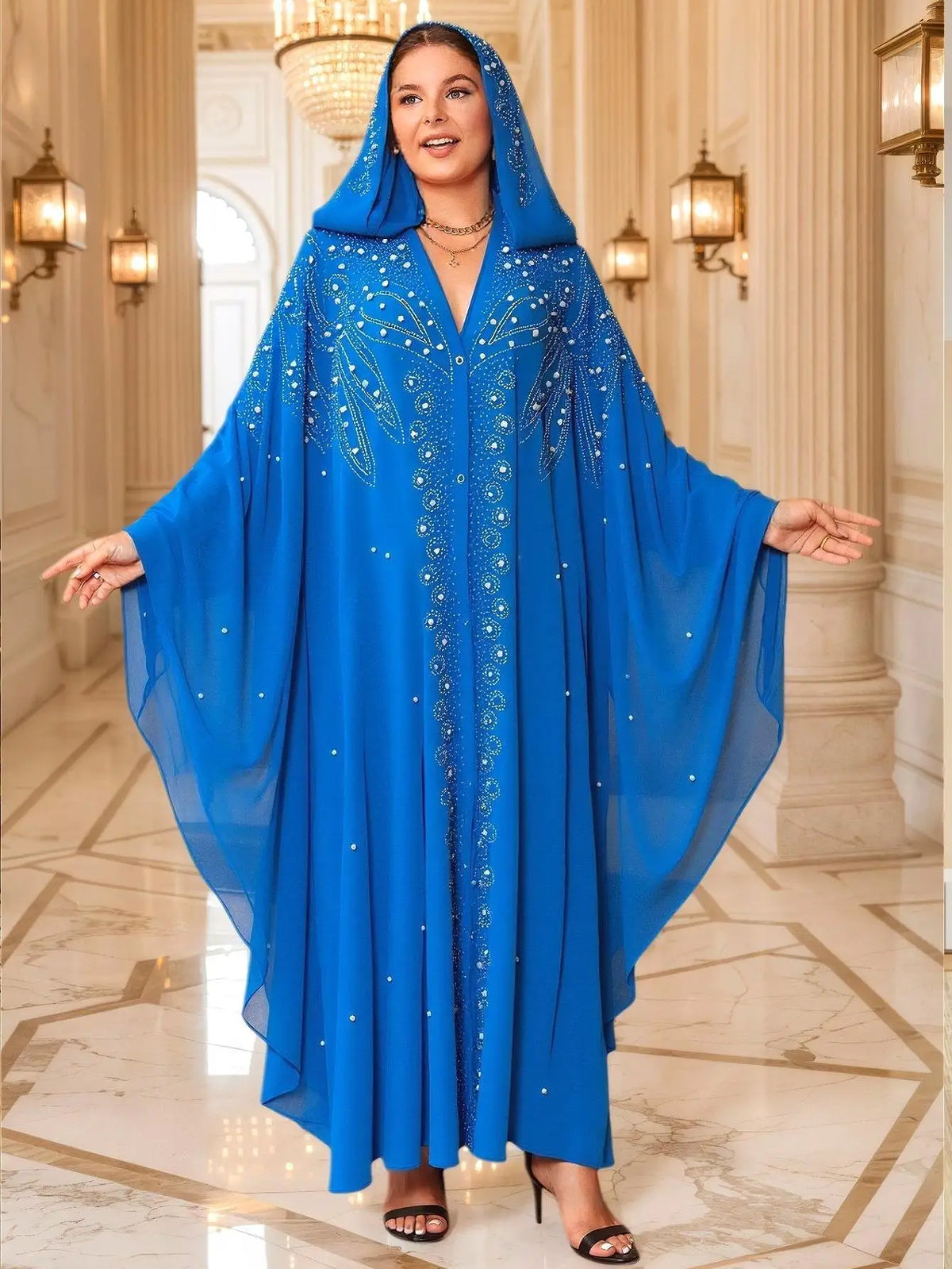 Una mujer modela un abaya maxi de color azul real fluida con mangas de murciélago en un entorno interior lujoso.