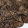 A close-up of a brown leopard print silk satin neckerchief hijab scarf fabric.