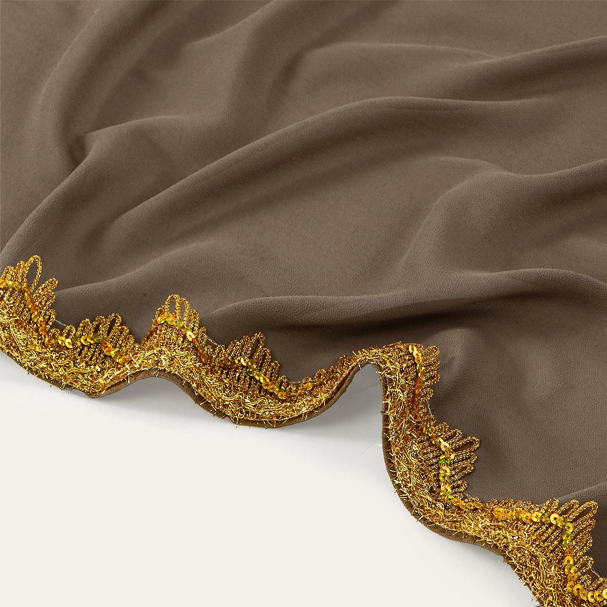 Nahaufnahme eines taupefarbenen Chiffonstoffs mit einem verzierten Goldverzierkantenrand.