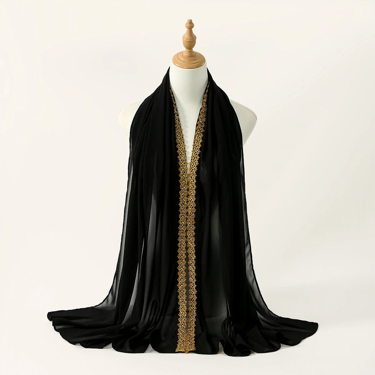 Bufanda/chal/hiyab de gasa negra con detalle de strass dorados, exhibida en un maniquí.