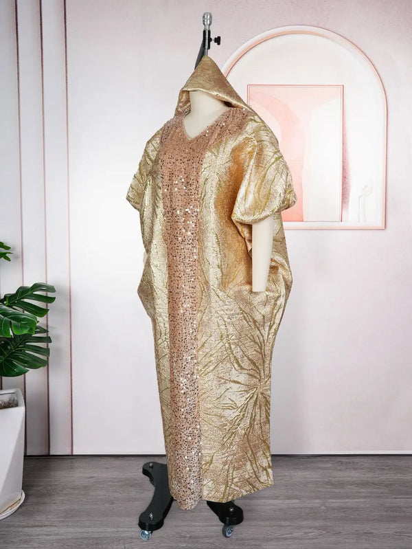 A gold sequin maxi dress with a headtie displayed on a mannequin against a pink wall.