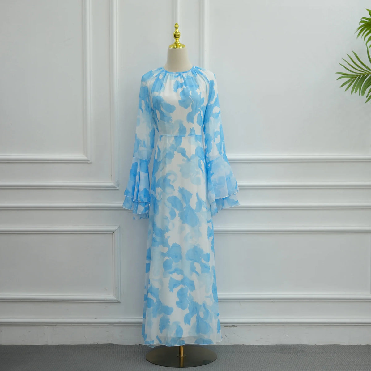Hellblaue floral gemusterte Abaya oder Kaftan-Kleid auf einem Mannequin vor einer weißen Wand.