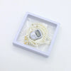 A silver digital counter bracelet is displayed in a white box surrounded by white prayer beads.