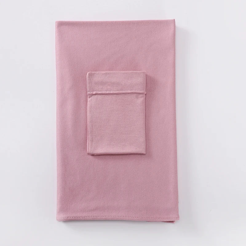 Un conjunto de dos piezas a juego de hijab de jersey color rosa empolvado suave, mostrado plano.