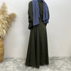 Vestido abaya verde oliva de largo completo con pañuelo morado a juego, exhibido contra una pared blanca.