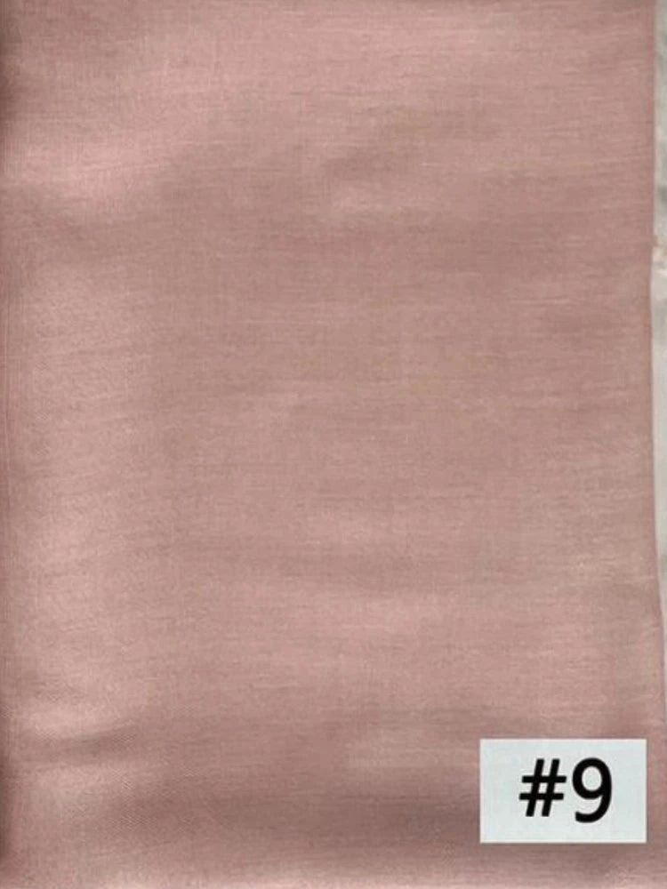 Un foulard modal rose pâle et doux est montré sur un fond uni.